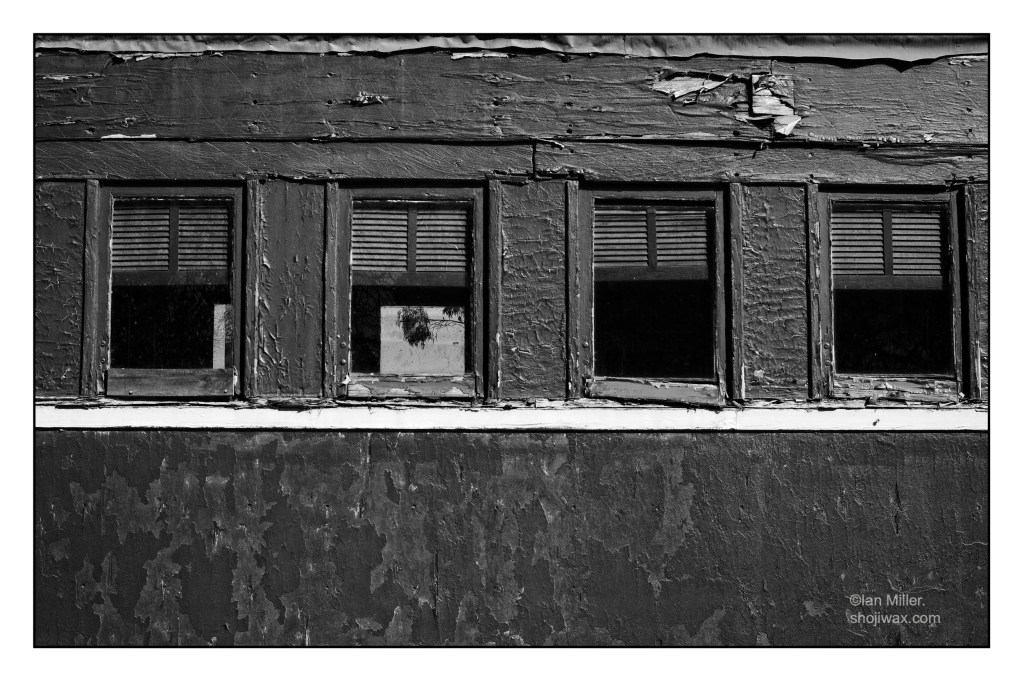Black and white photo of old train carriage with cracked flaking paint.