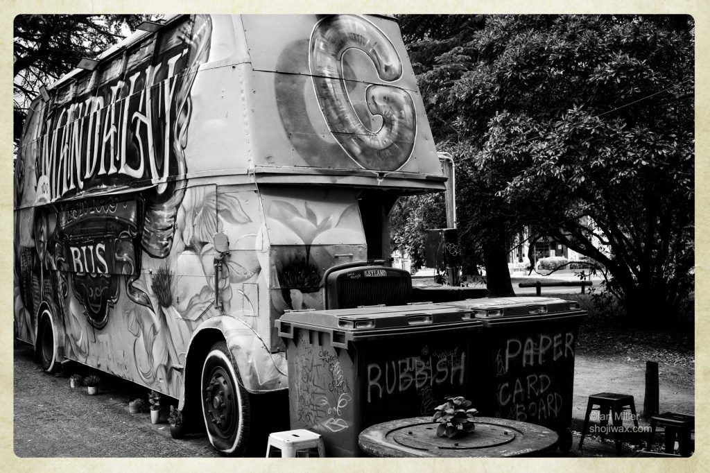 Black and white photo of an old double decker bus that has been transmogrified into a fast food truck.
Covered in graffiti art.