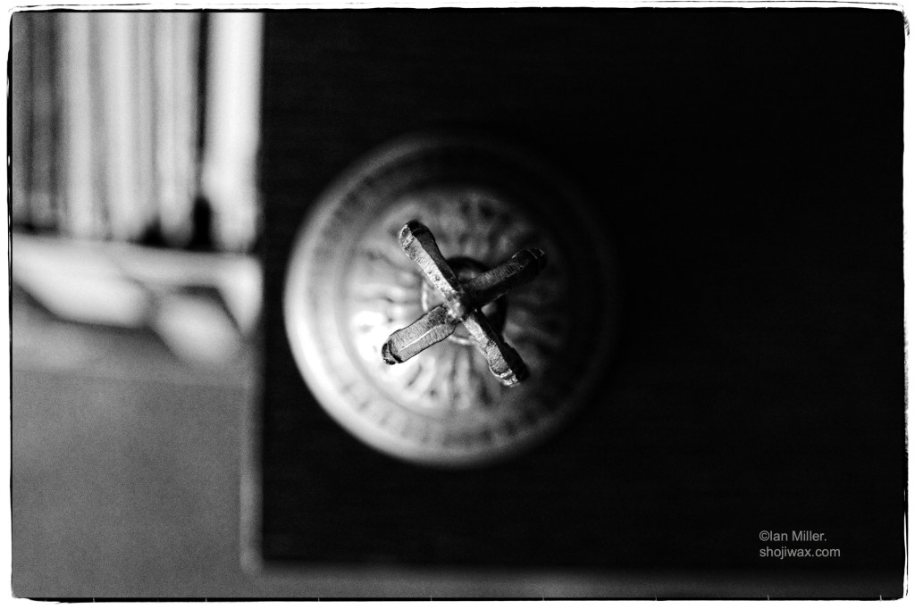 Monochrome photo of a tibetan bell taken from above. It is half hidden in darkness.