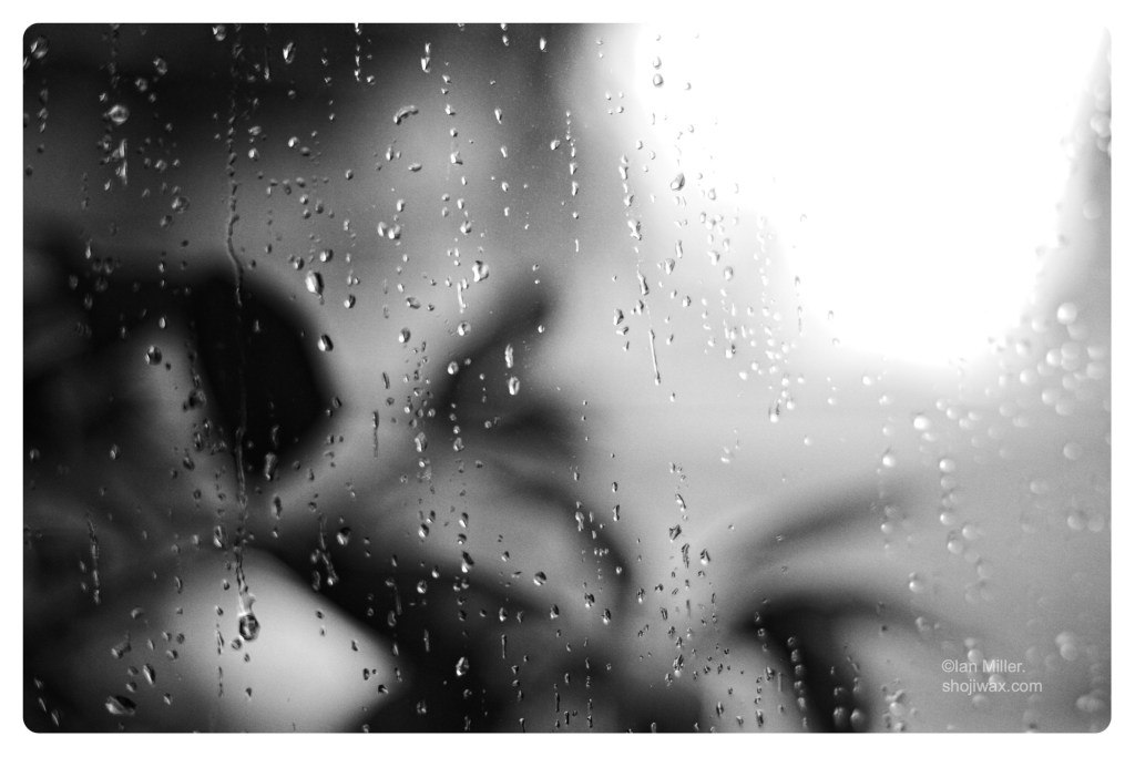 Monochrome photo of window with raindrops.