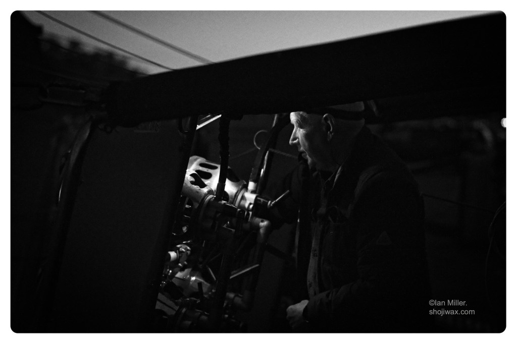 Monochrome photo close up of man in profile and shadow lit by the light of his hot air balloon gas burners.