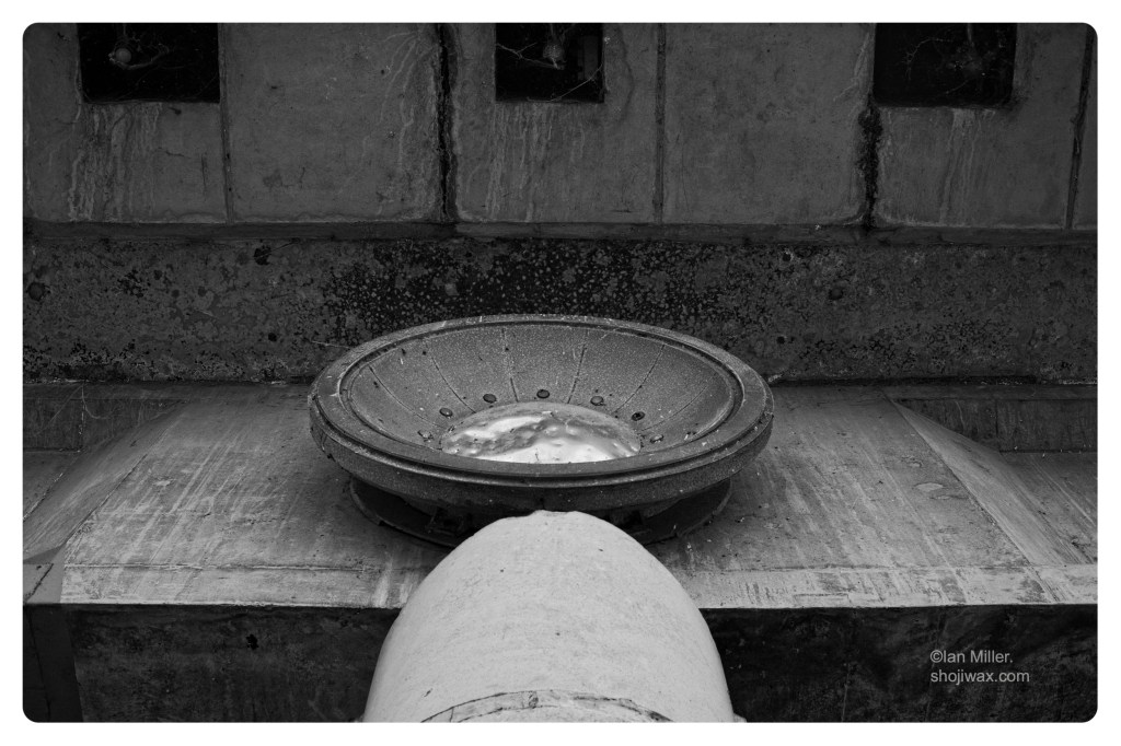 Monochrome photo of silver coloured bowl shape set in various concrete blocks.