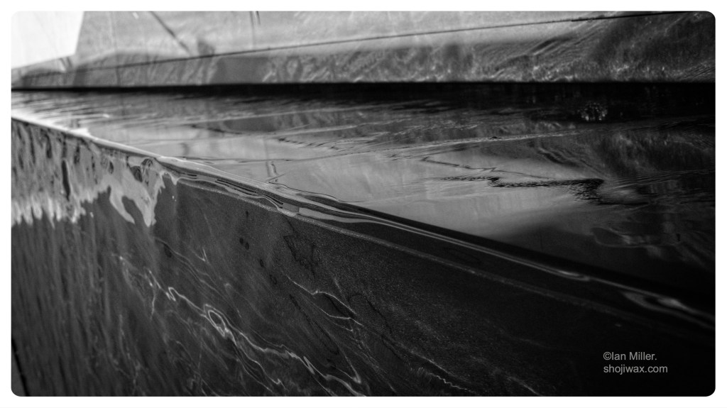 Monochrome abstract photo of water moving across angled surfaces.