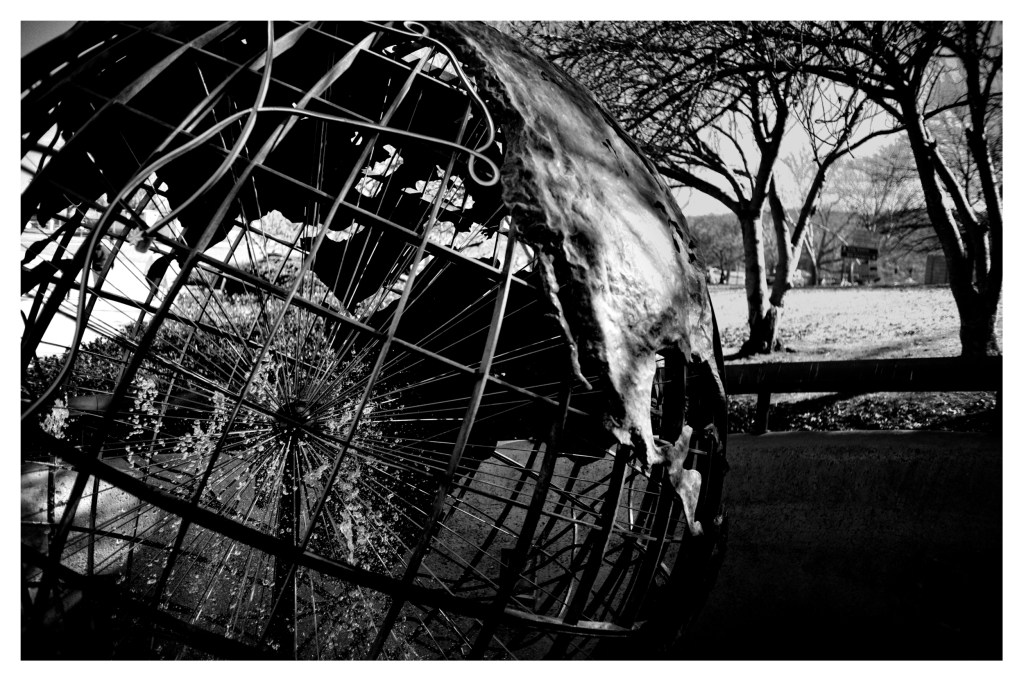 Monochrome photo of a steel globe sculpture including internal water fountain.