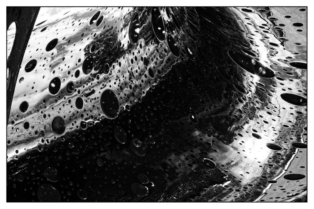 Monochrome photo detail of stainless steel sculpture impregnated with many different sized holes