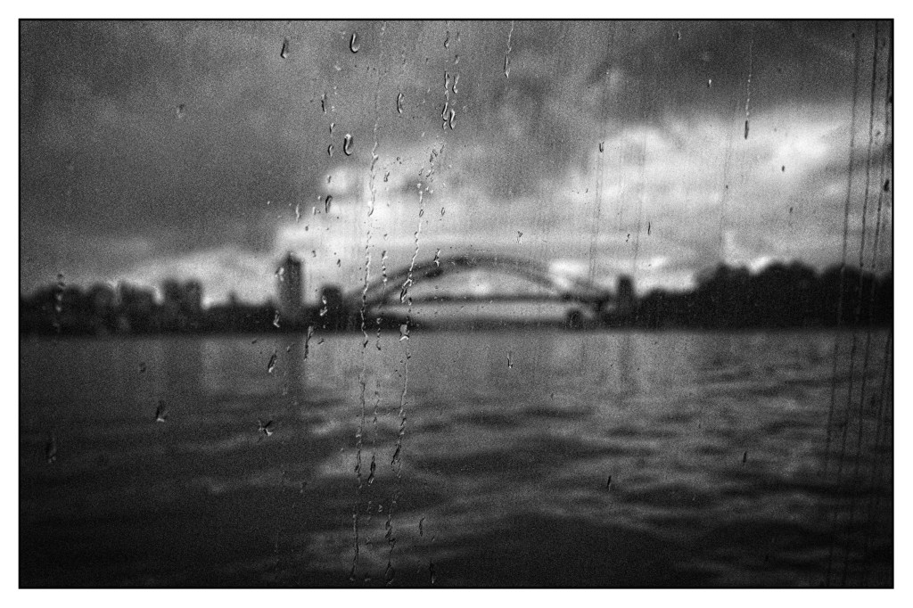 Monochrome photo of iconic bridge seen through the blurring wet glass of a ferry.