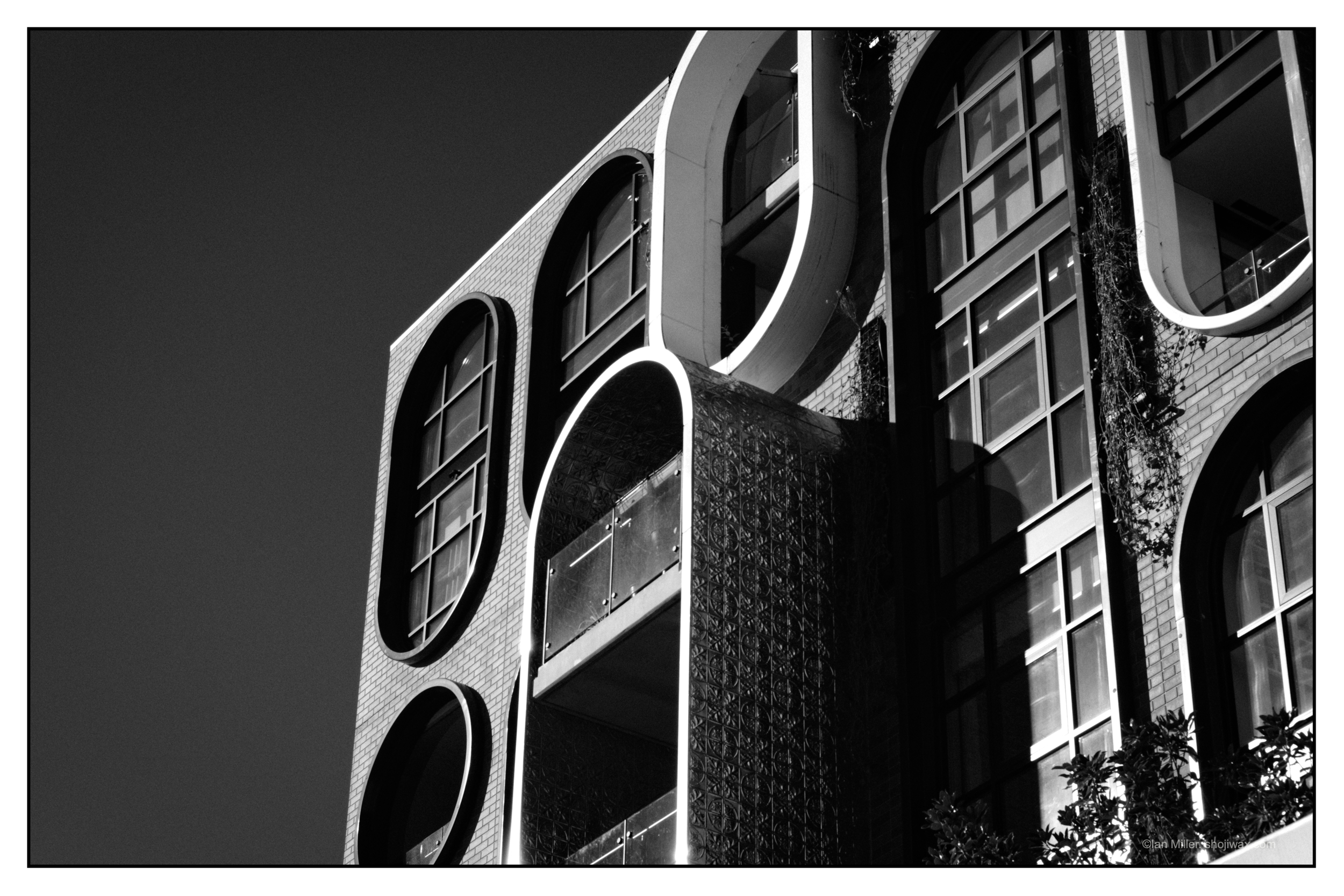 Monochrome photo of the corner of a modern building with oval windows;
