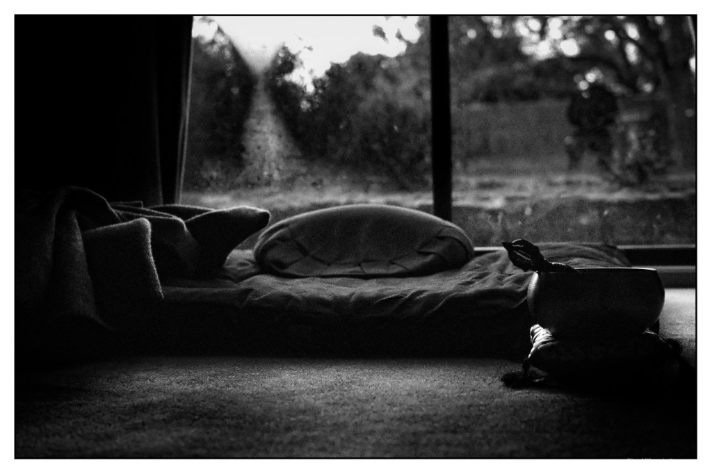 Monochrome photo of a meditation cushion. In the foreground there is a tibetan meditation bell.