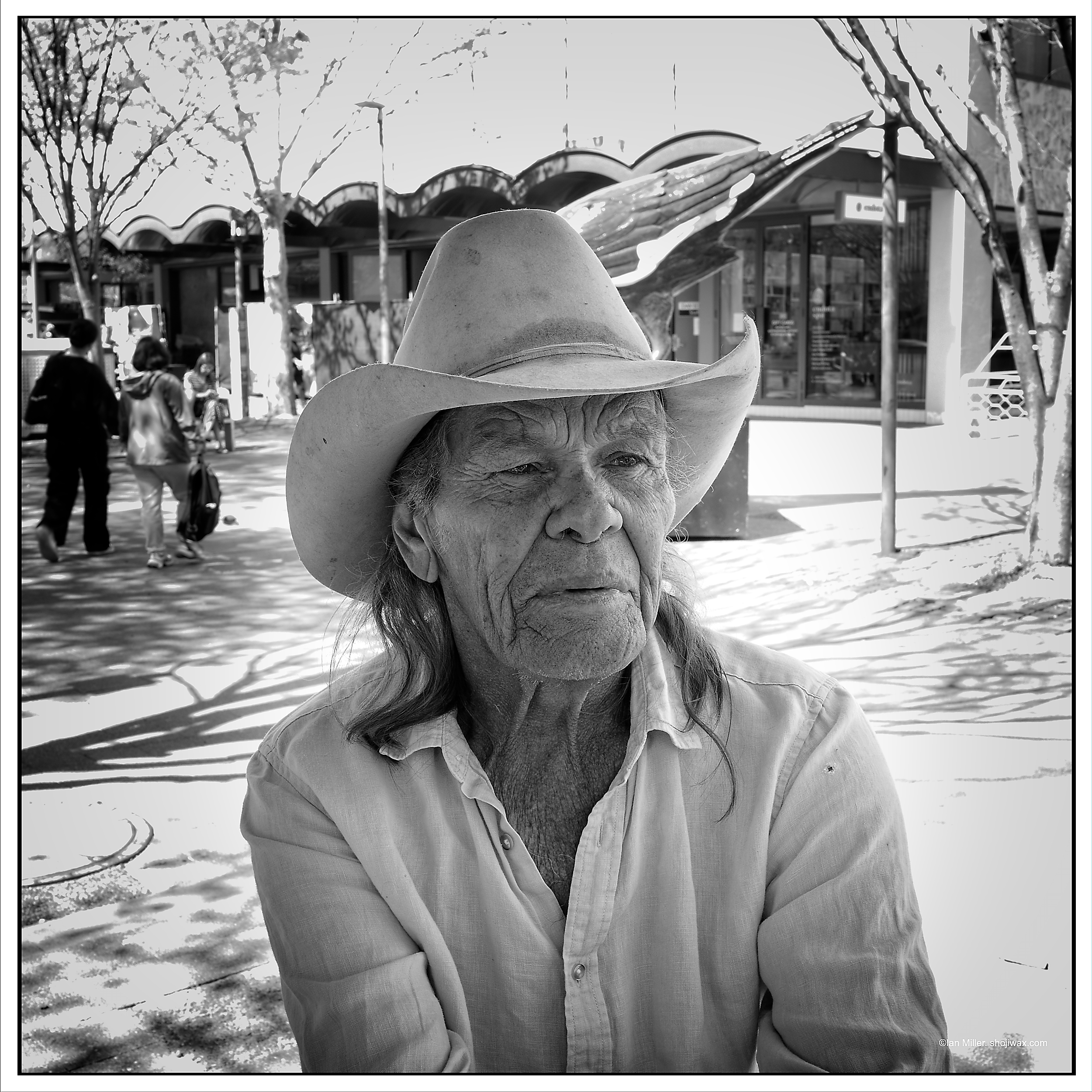 Monochrome photo of older man with long hair wearing a cowboy hat.